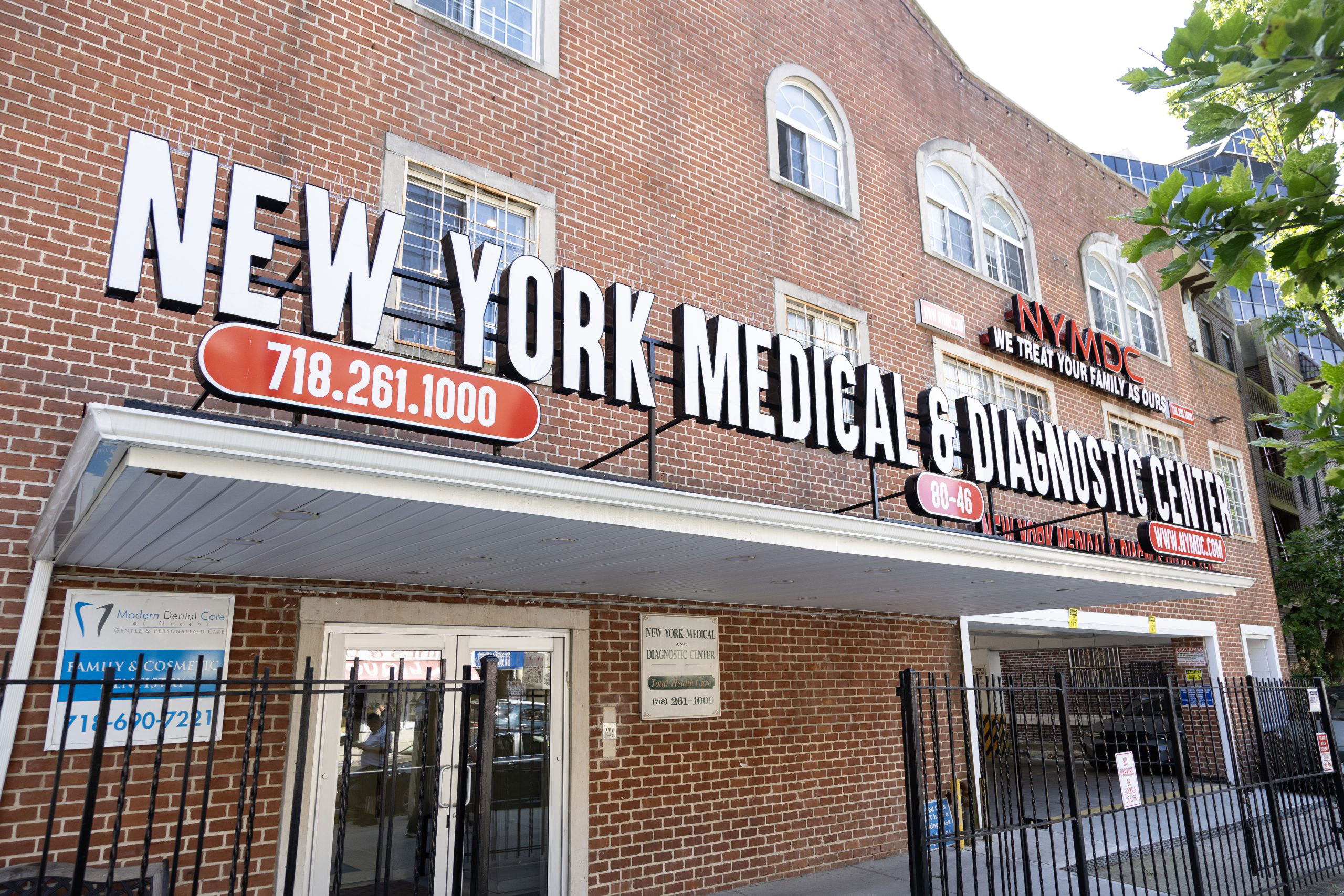 The image is a photograph of a sign for the 'New York Medical & Diagnostic Center' mounted on the side of a brick building, with a phone number and address provided.