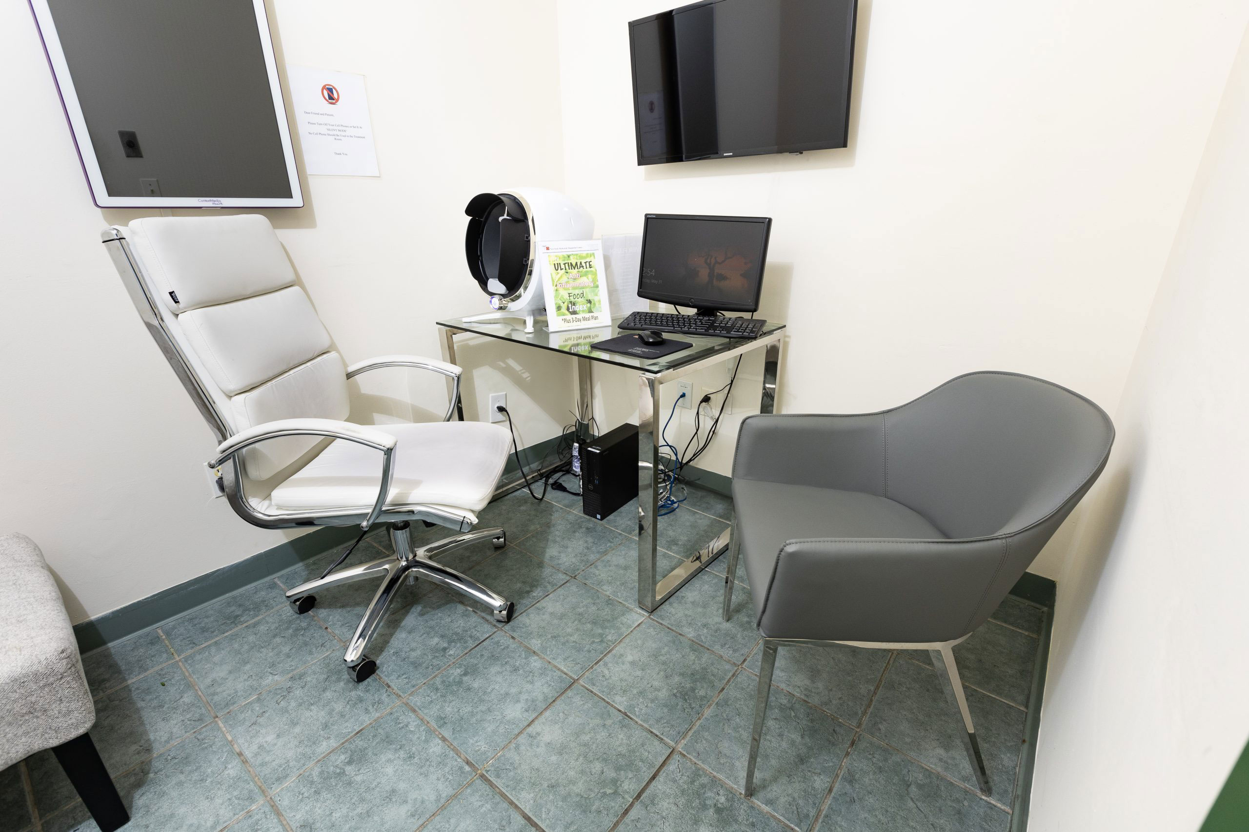 The image shows an interior space that appears to be a waiting area or consultation room, with a desk and chair setup, a computer monitor, and a waiting chair.