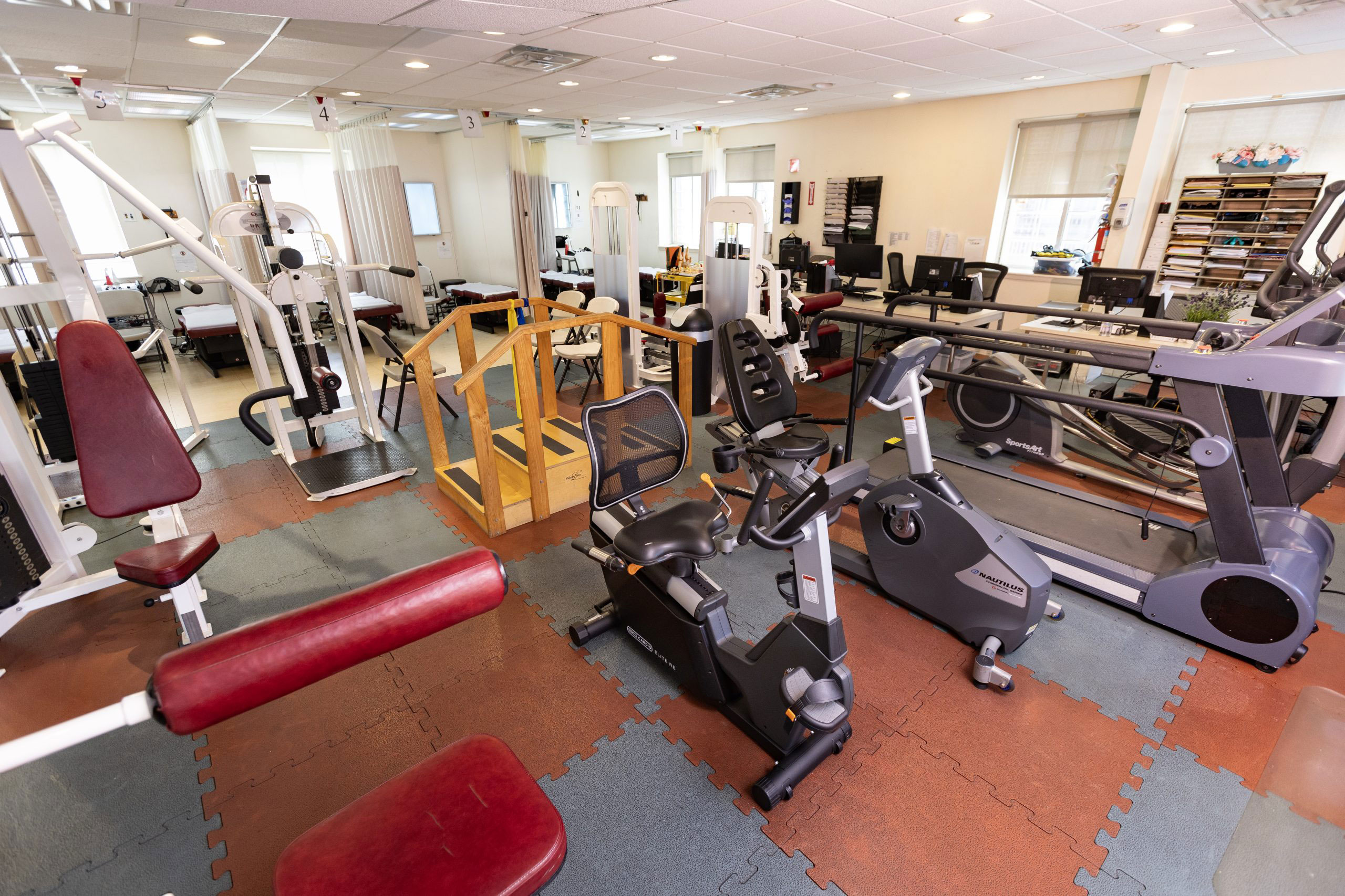 The image shows an interior space that appears to be a gym, with various exercise equipment such as weightlifting machines and cardio equipment.