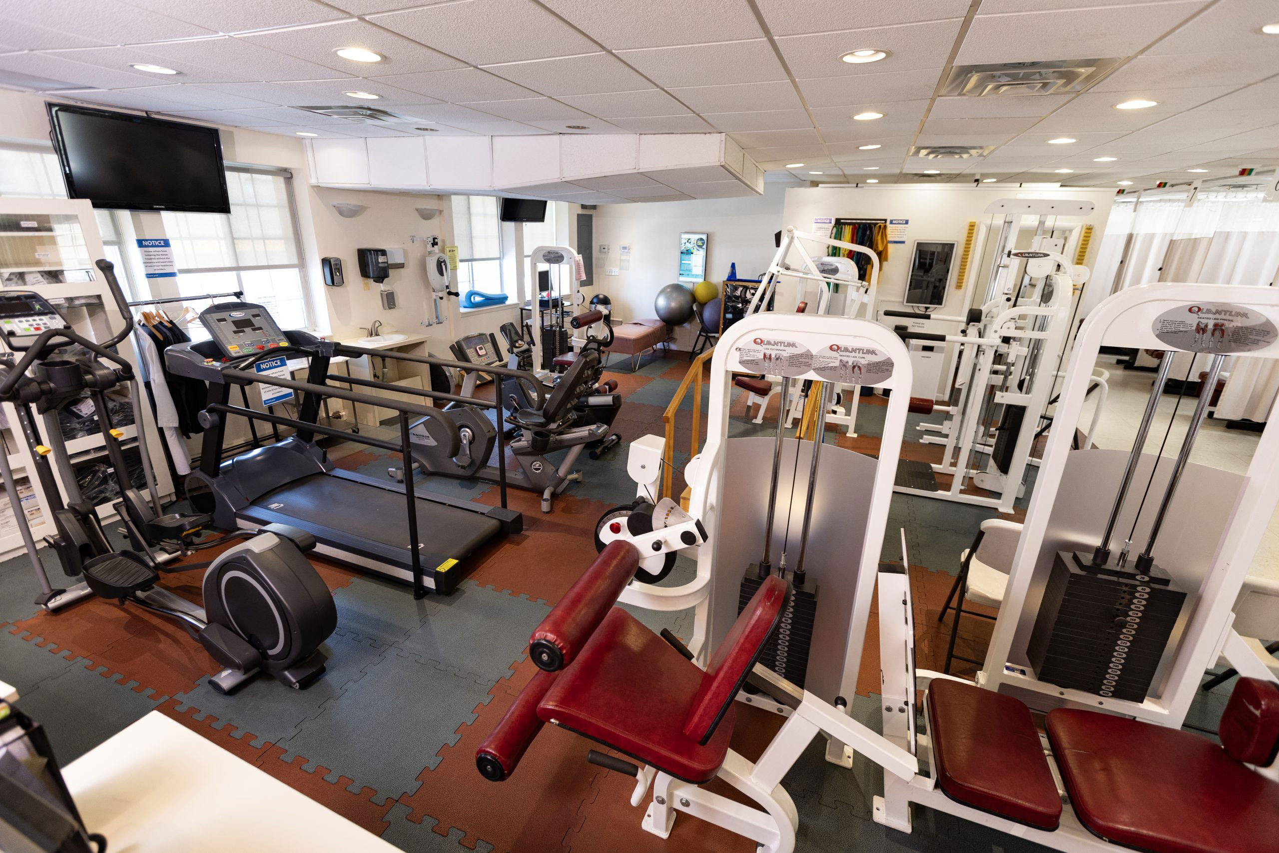The image depicts an interior gym space filled with various exercise equipment.