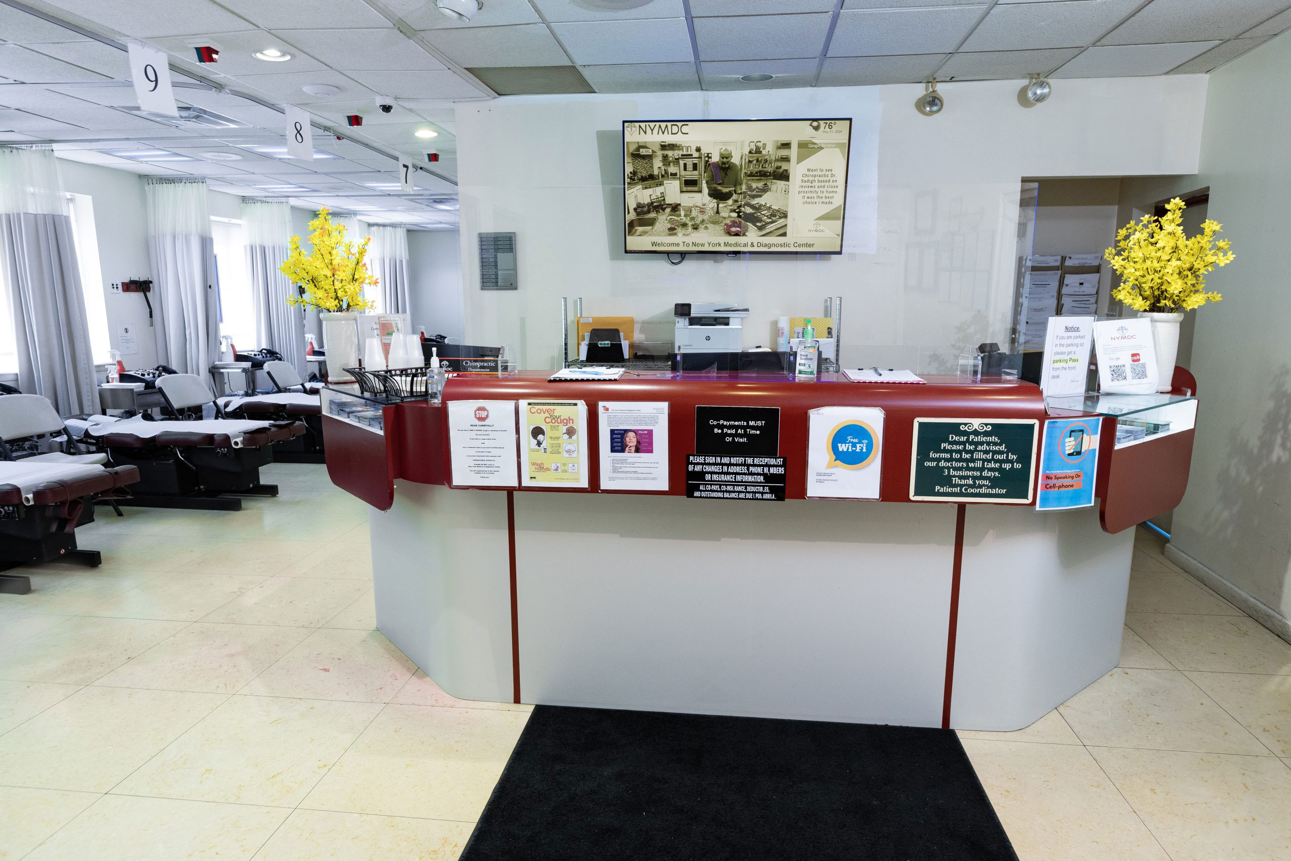 The image shows an interior of a dental or medical office with a reception desk, a waiting area, and various signs and posters.