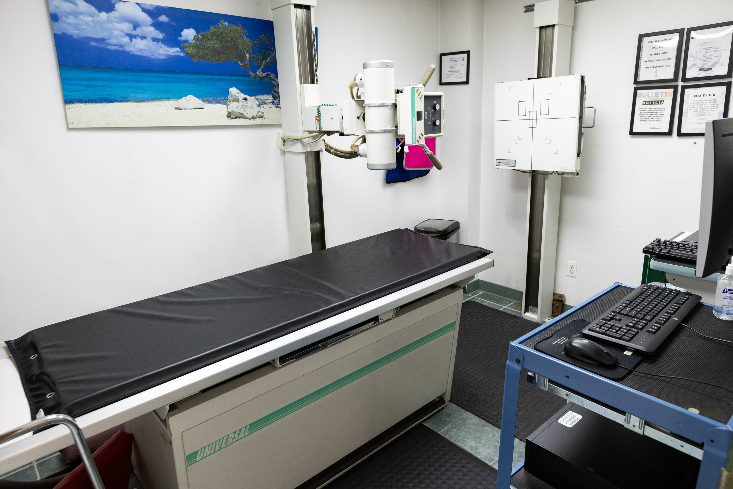 The image shows an interior view of a medical office, featuring a dental chair and a computer monitor on a desk with a keyboard.